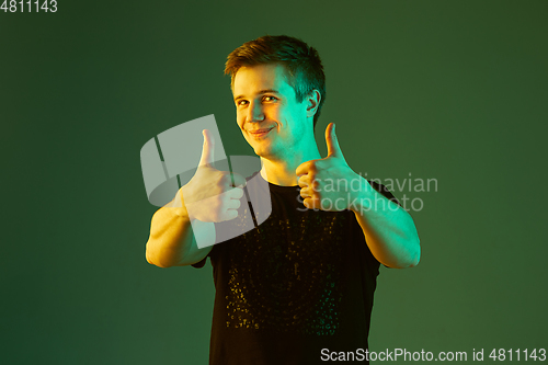 Image of Caucasian man\'s portrait isolated on green studio background in neon light