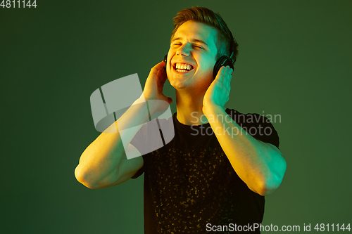 Image of Caucasian man\'s portrait isolated on green studio background in neon light