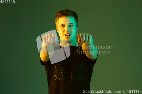 Image of Caucasian man\'s portrait isolated on green studio background in neon light