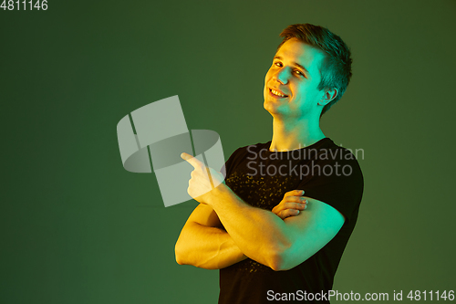 Image of Caucasian man\'s portrait isolated on green studio background in neon light