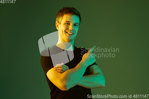 Image of Caucasian man\'s portrait isolated on green studio background in neon light
