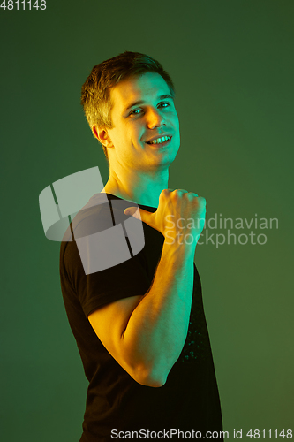 Image of Caucasian man\'s portrait isolated on green studio background in neon light