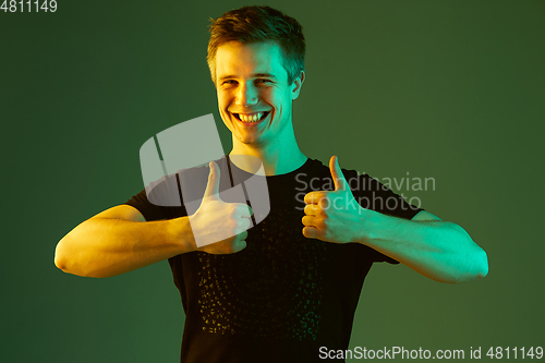 Image of Caucasian man\'s portrait isolated on green studio background in neon light