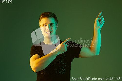 Image of Caucasian man\'s portrait isolated on green studio background in neon light
