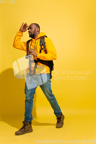 Image of Full length portrait of a cheerful young african tourist guy isolated on yellow background