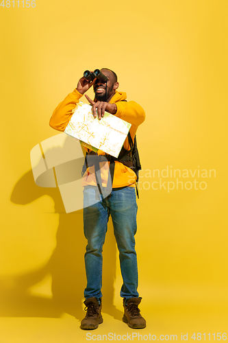 Image of Full length portrait of a cheerful young african tourist guy isolated on yellow background