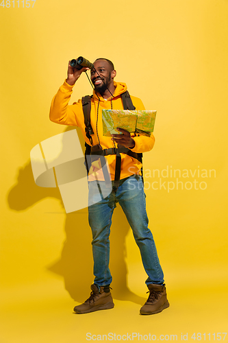 Image of Full length portrait of a cheerful young african tourist guy isolated on yellow background