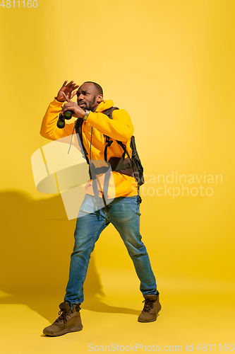 Image of Full length portrait of a cheerful young african tourist guy isolated on yellow background