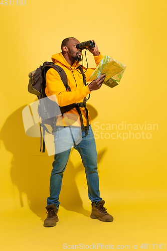 Image of Full length portrait of a cheerful young african tourist guy isolated on yellow background