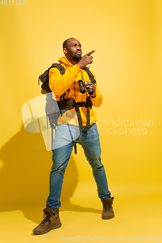 Image of Full length portrait of a cheerful young african tourist guy isolated on yellow background