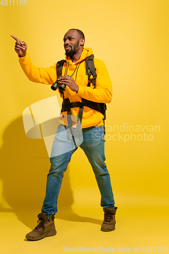 Image of Full length portrait of a cheerful young african tourist guy isolated on yellow background