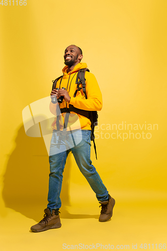 Image of Full length portrait of a cheerful young african tourist guy isolated on yellow background