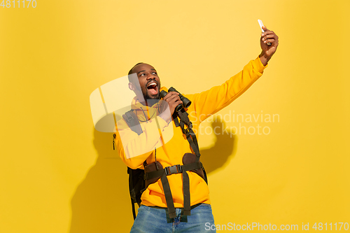 Image of Full length portrait of a cheerful young african tourist guy isolated on yellow background