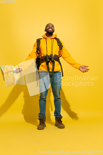 Image of Full length portrait of a cheerful young african tourist guy isolated on yellow background