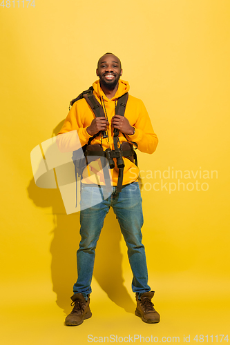 Image of Full length portrait of a cheerful young african tourist guy isolated on yellow background