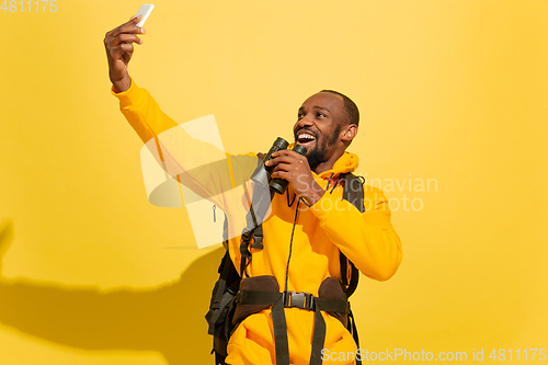 Image of Full length portrait of a cheerful young african tourist guy isolated on yellow background