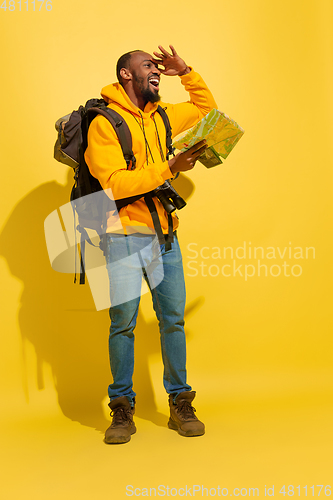 Image of Full length portrait of a cheerful young african tourist guy isolated on yellow background