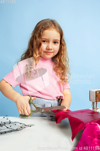 Image of Little girl dreaming about future profession of seamstress