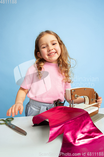 Image of Little girl dreaming about future profession of seamstress