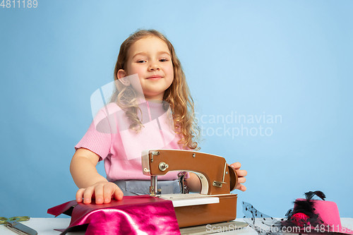 Image of Little girl dreaming about future profession of seamstress