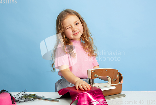 Image of Little girl dreaming about future profession of seamstress