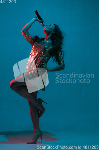 Image of Caucasian female singer portrait isolated on blue studio background in neon light