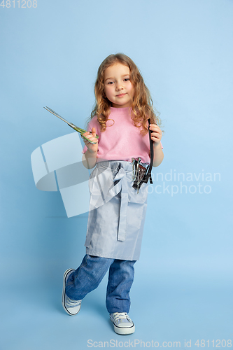 Image of Little girl dreaming about future profession of seamstress