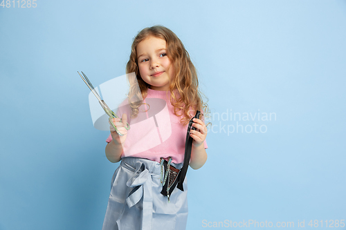 Image of Little girl dreaming about future profession of seamstress