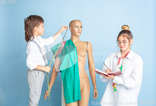 Image of Little boy and girl dreaming about future profession of seamstress