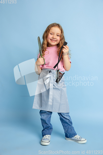 Image of Little girl dreaming about future profession of seamstress