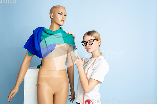 Image of Young girl dreaming about future profession of seamstress