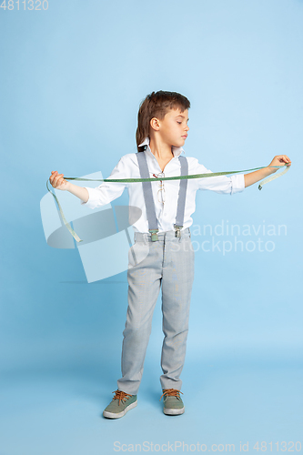Image of Little boy dreaming about future profession of seamstress