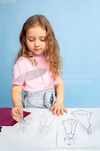 Image of Little girl dreaming about future profession of seamstress