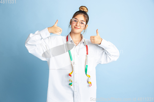 Image of Young girl dreaming about future profession of seamstress