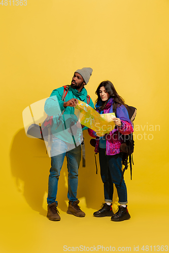 Image of Portrait of a cheerful young tourist couple isolated on yellow background