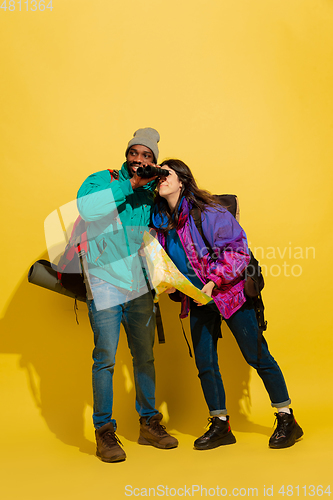 Image of Portrait of a cheerful young tourist couple isolated on yellow background