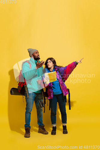Image of Portrait of a cheerful young tourist couple isolated on yellow background