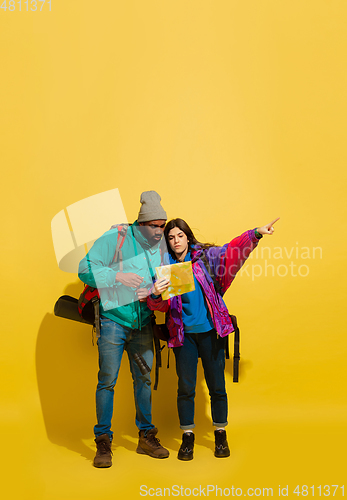 Image of Portrait of a cheerful young tourist couple isolated on yellow background