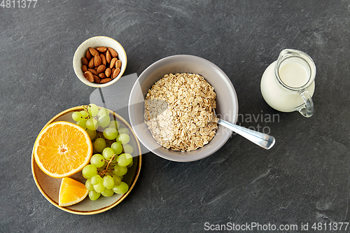 Image of oatmeal with fruits, almond nuts and jug of milk