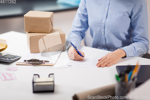 Image of close up of woman filling postal form at office