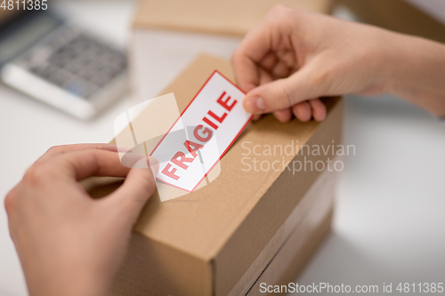 Image of woman sticking fragile mark to parcel box