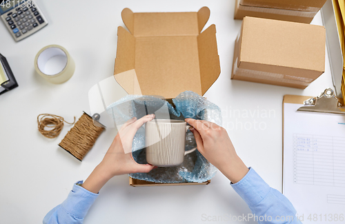 Image of hands packing mug to parcel box at post office