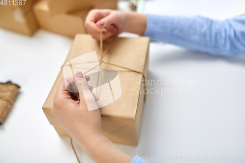 Image of hands packing parcel and tying rope at post office