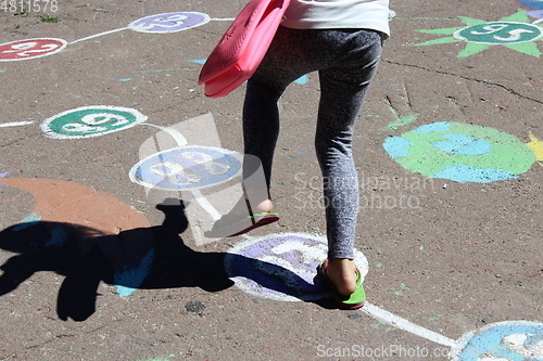 Image of girl runs on the childish drawings on the asphalt