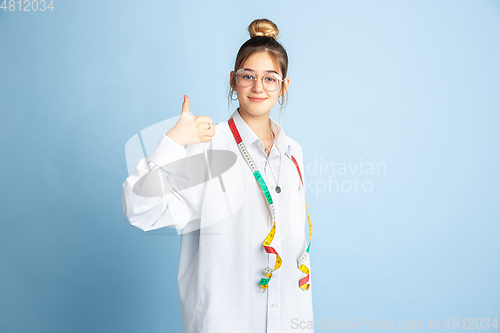 Image of Young girl dreaming about future profession of seamstress