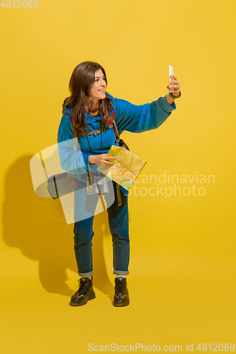 Image of Full length portrait of a cheerful young caucasian tourist girl isolated on yellow background