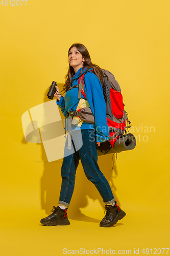 Image of Full length portrait of a cheerful young caucasian tourist girl isolated on yellow background