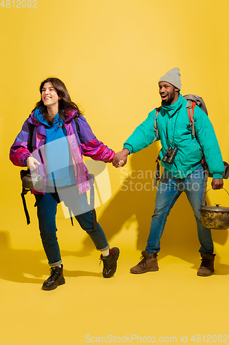 Image of Portrait of a cheerful young tourist couple isolated on yellow background