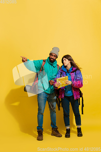 Image of Portrait of a cheerful young tourist couple isolated on yellow background