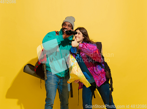 Image of Portrait of a cheerful young tourist couple isolated on yellow background